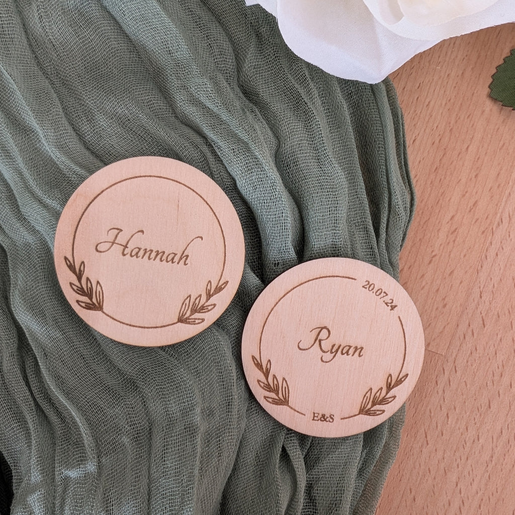 Two circle place names with engraved names on a green fabric background