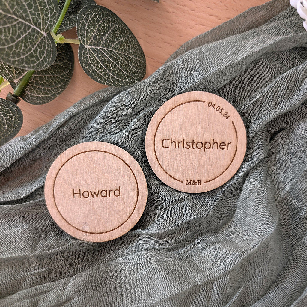 Two circle place names with engraved names on a green fabric background