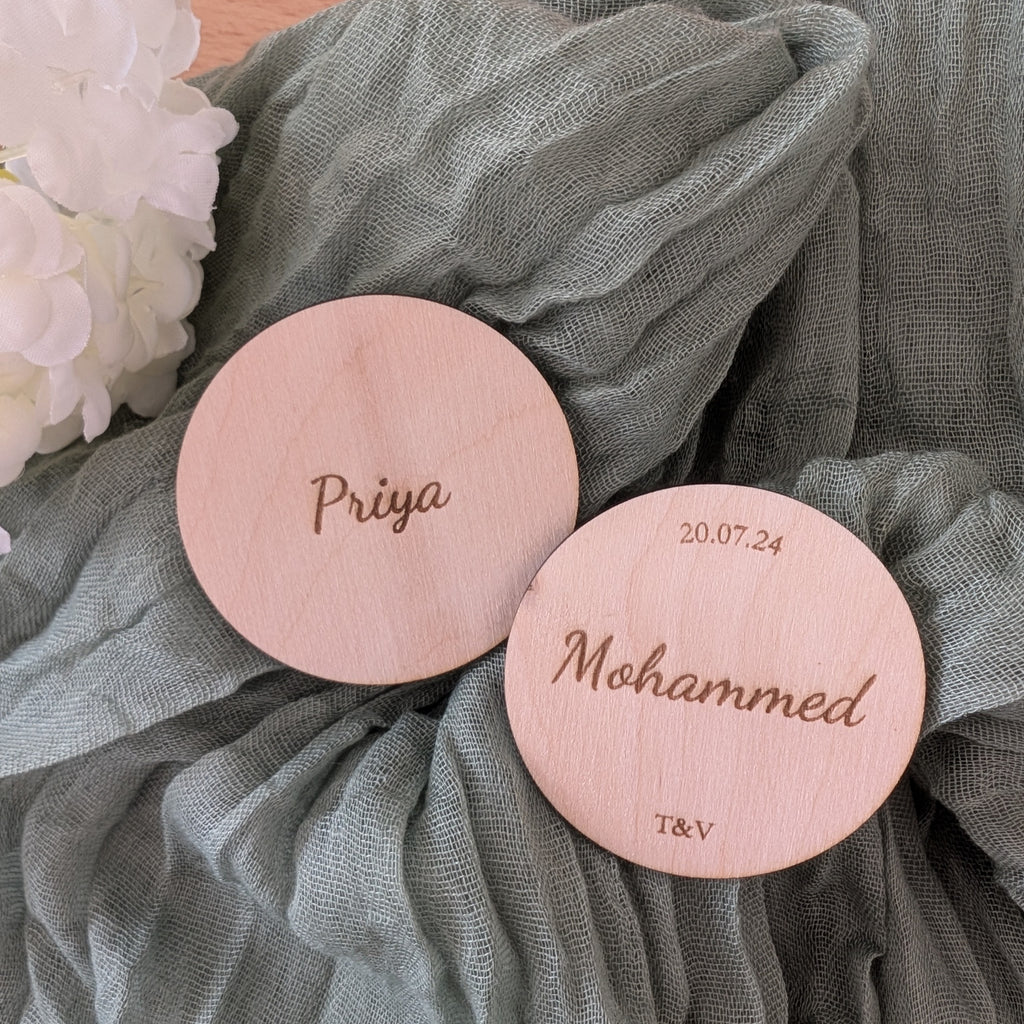 Two circle place names with engraved names on a textured green fabric background