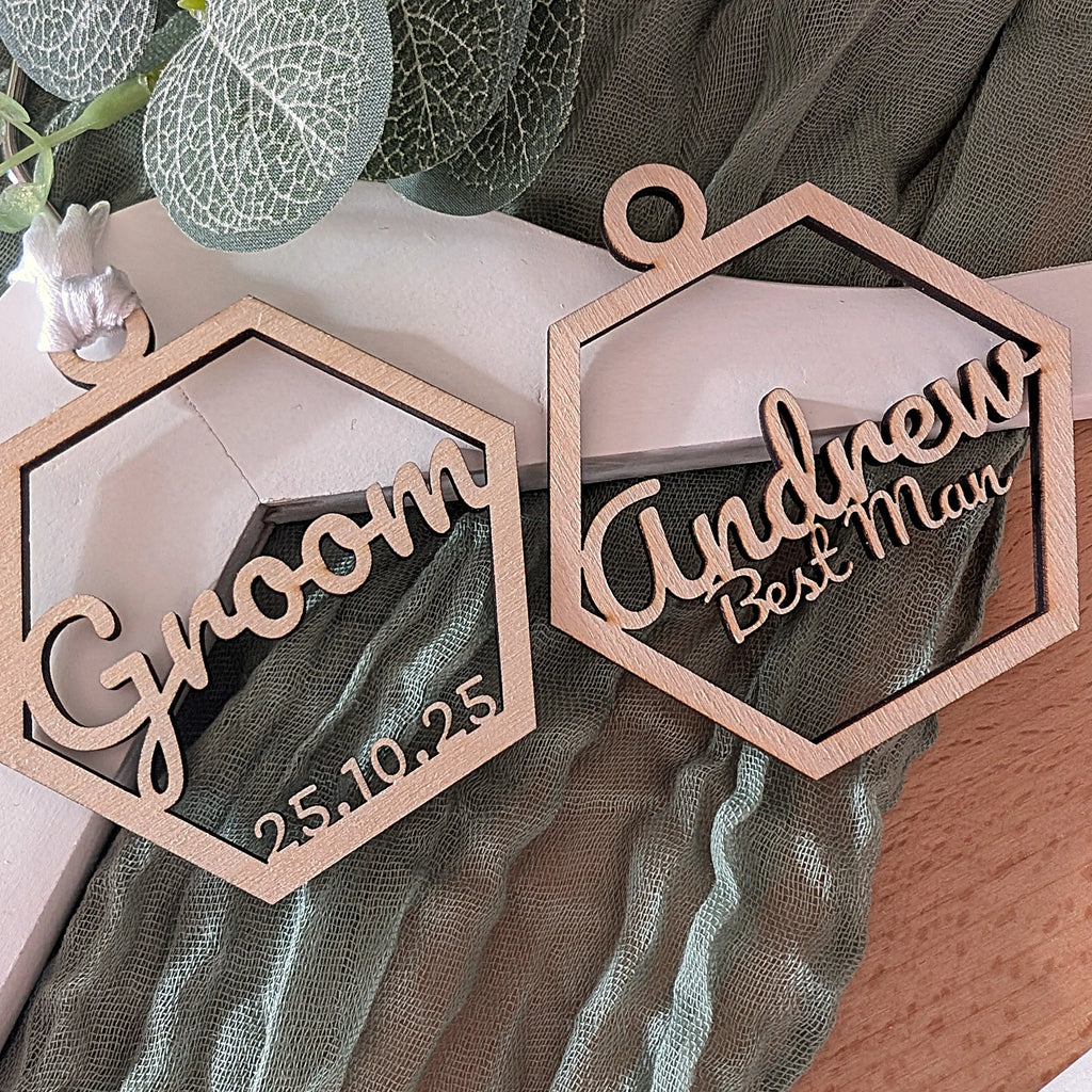 Wooden name tags for groom and best man with personalized text on a decorative background.