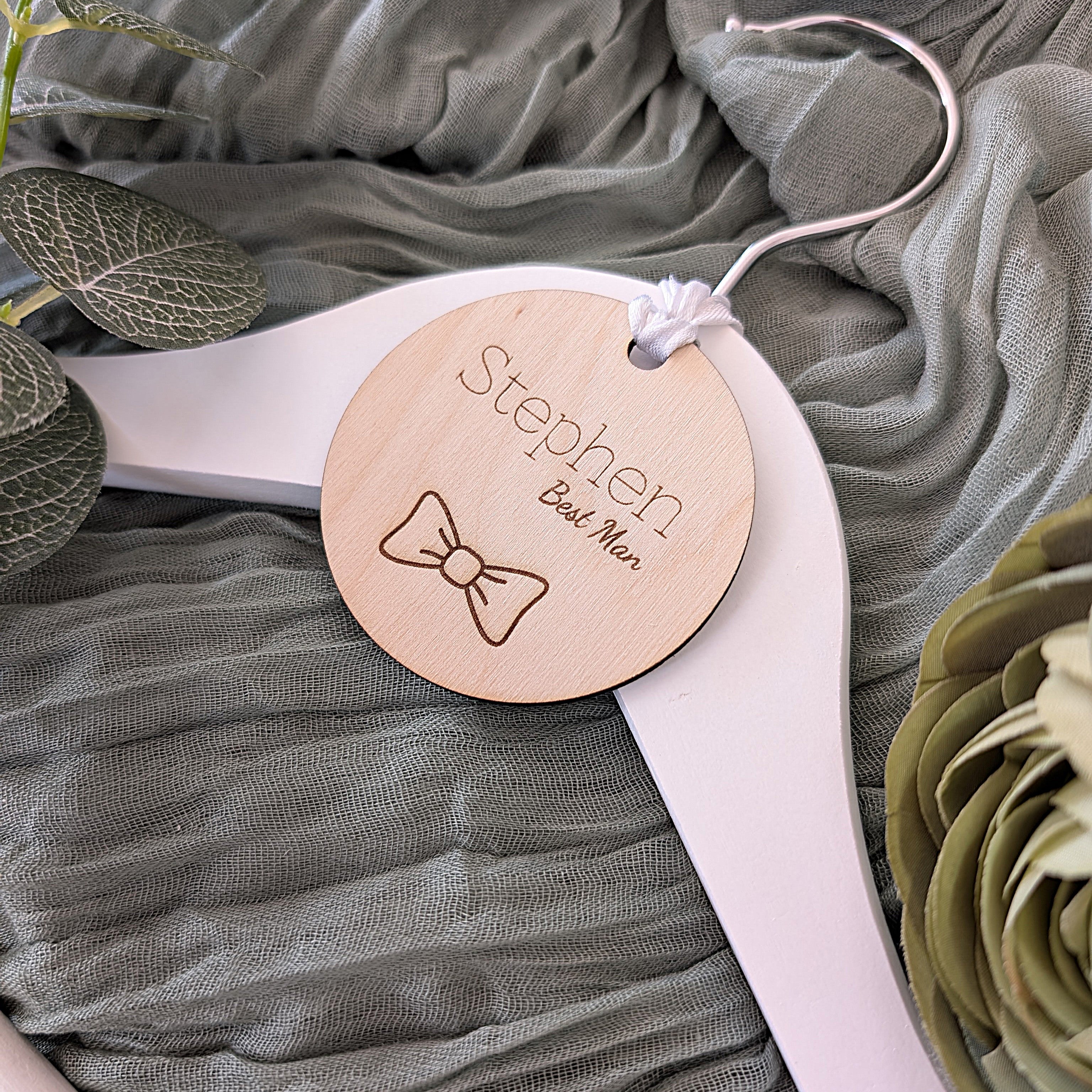 Personalized wooden tag on a white hanger with greenery in the background