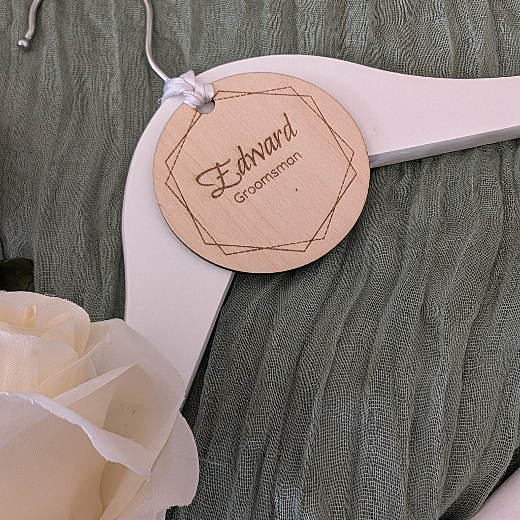 Wooden name tag on a white hanger with flowers in the foreground