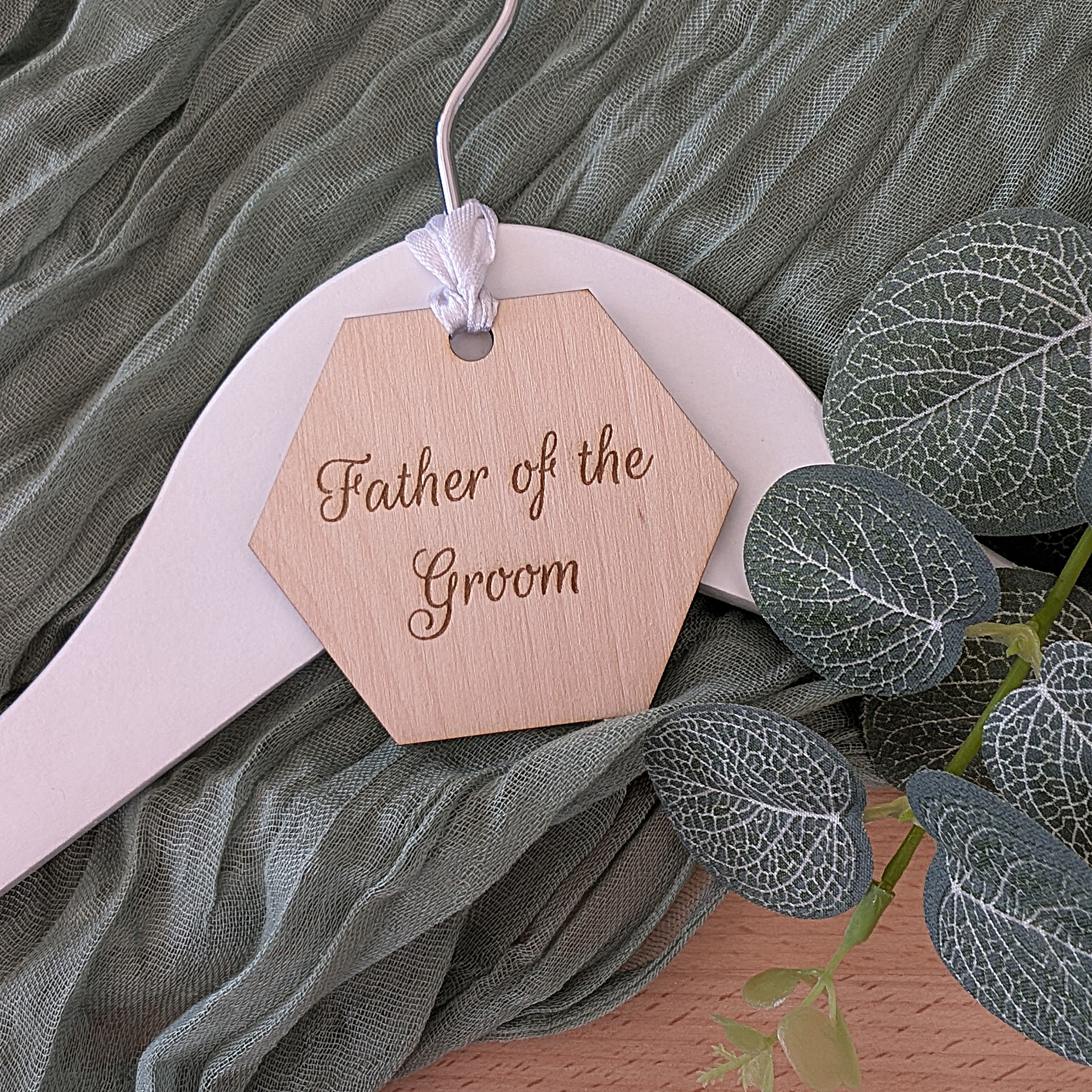 Wooden tag with 'Father of the Groom' text on a green fabric background