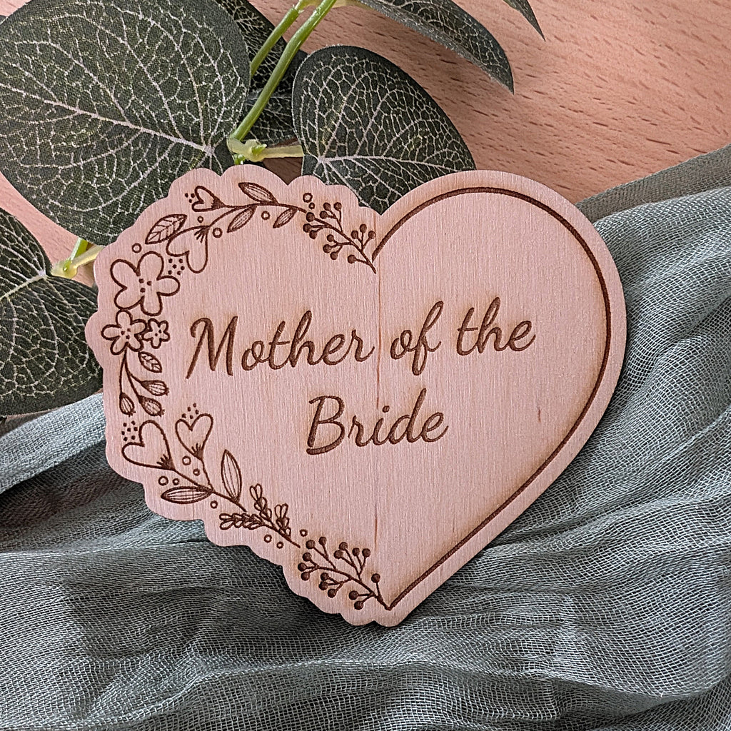 Heart-shaped wooden plaque with 'Mother of the Bride' engraving on a fabric background