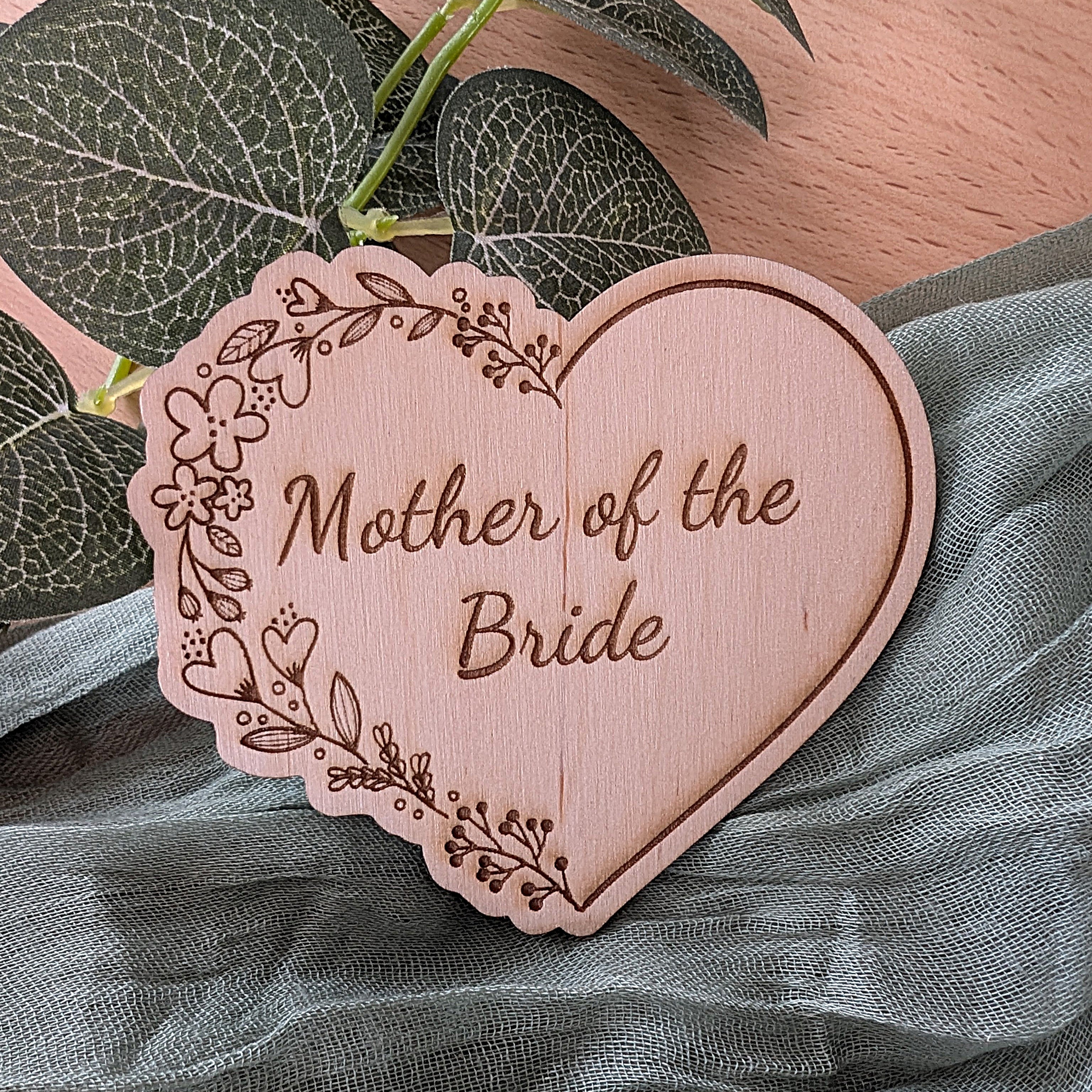 Heart-shaped wooden plaque with 'Mother of the Bride' engraving on a fabric background