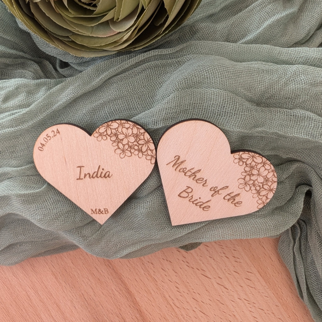 Heart-shaped wooden tags with engraved text on a green fabric background