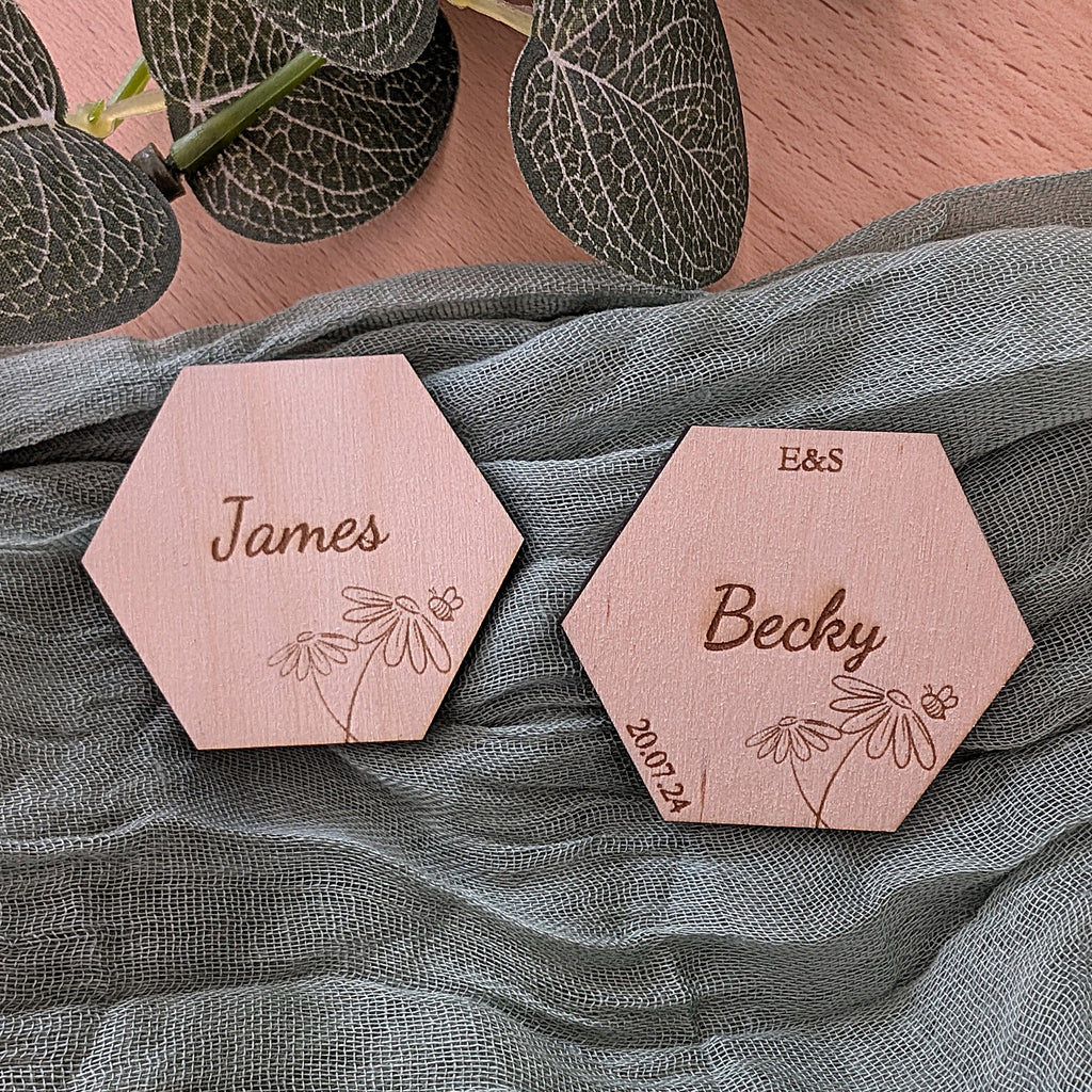 Hexagonal wooden name tags with engraved names on a textured fabric background