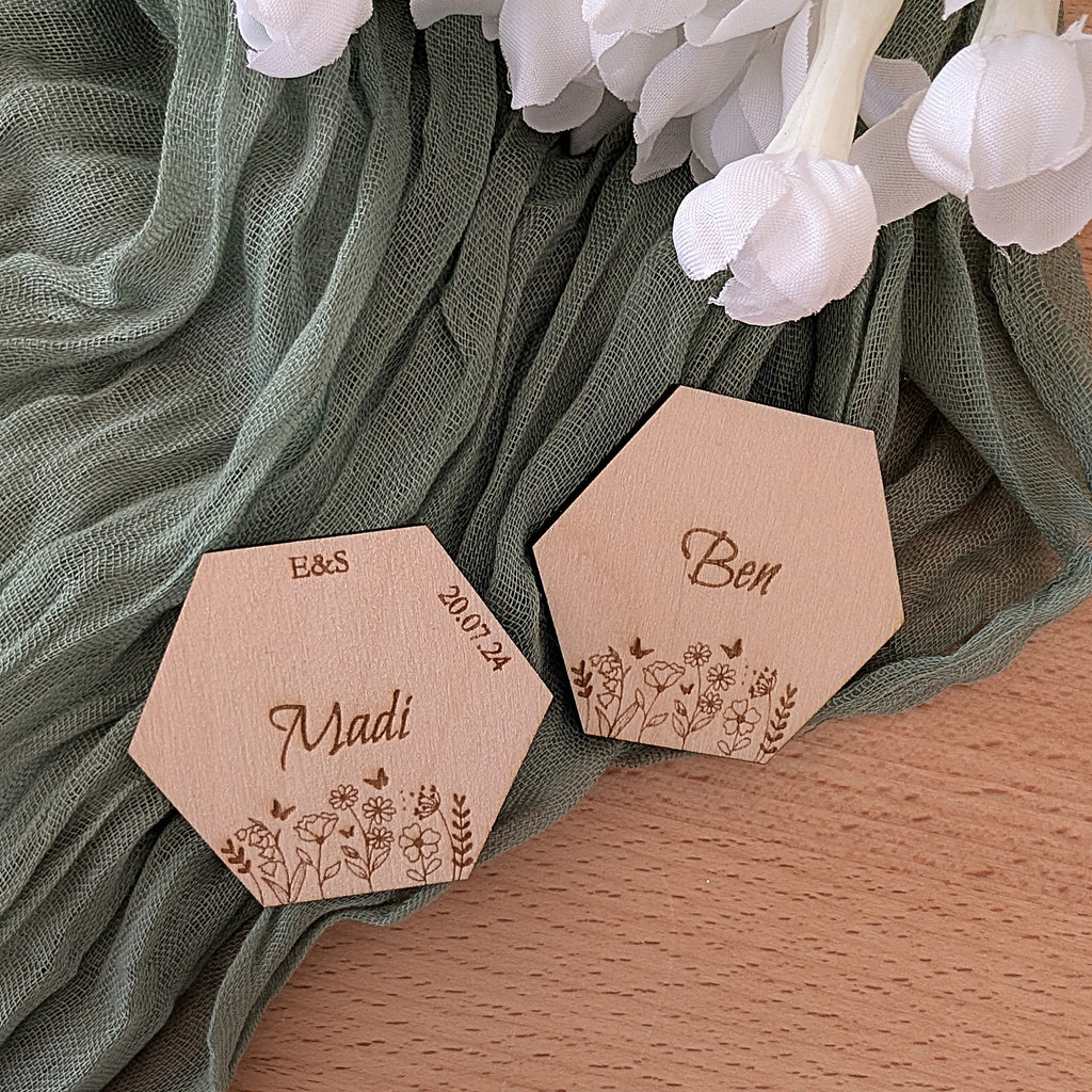 Hexagonal wooden name tags with engraved names on a green fabric background