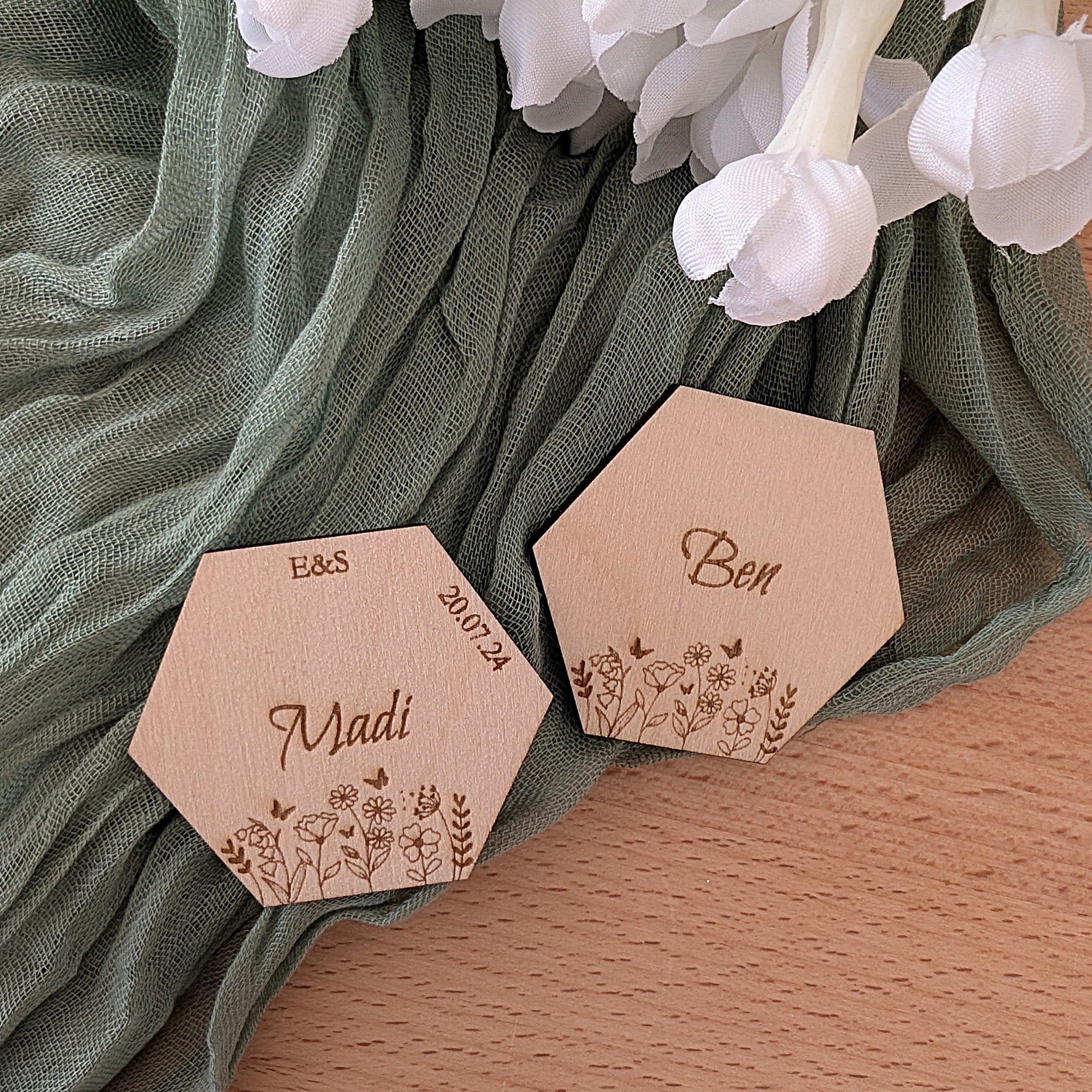 Hexagonal wooden name tags with engraved names on a green fabric background