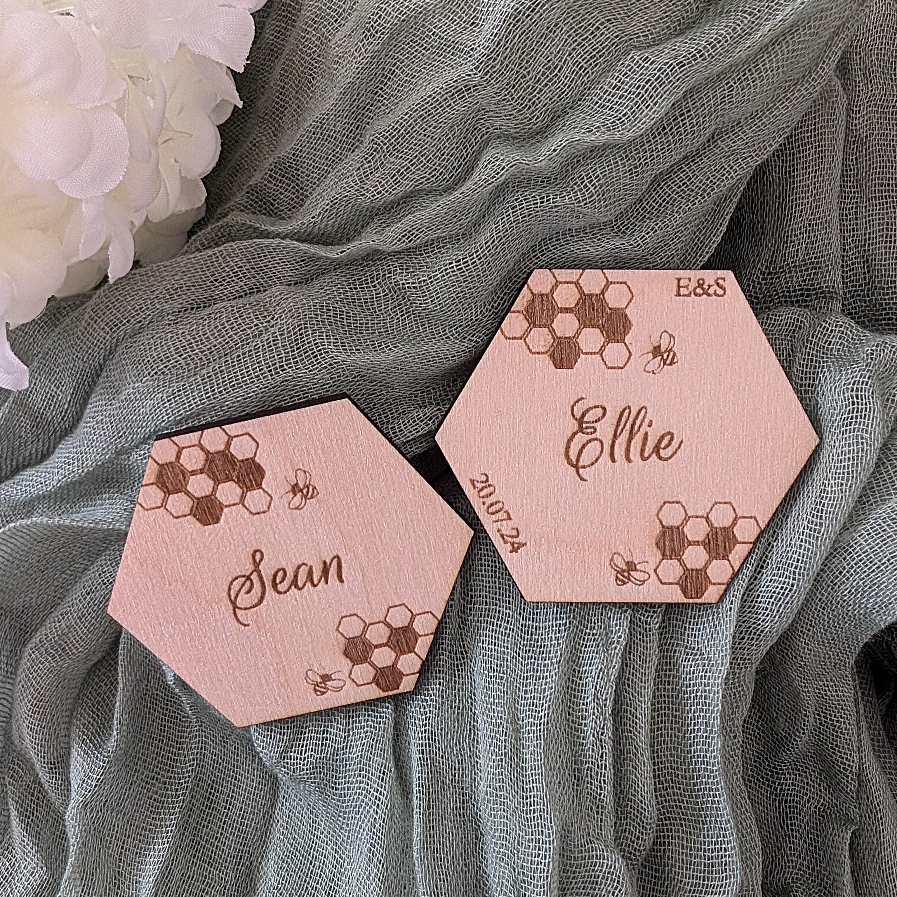 Hexagonal wooden coasters with engraved names and honeycomb patterns on a textured fabric background.