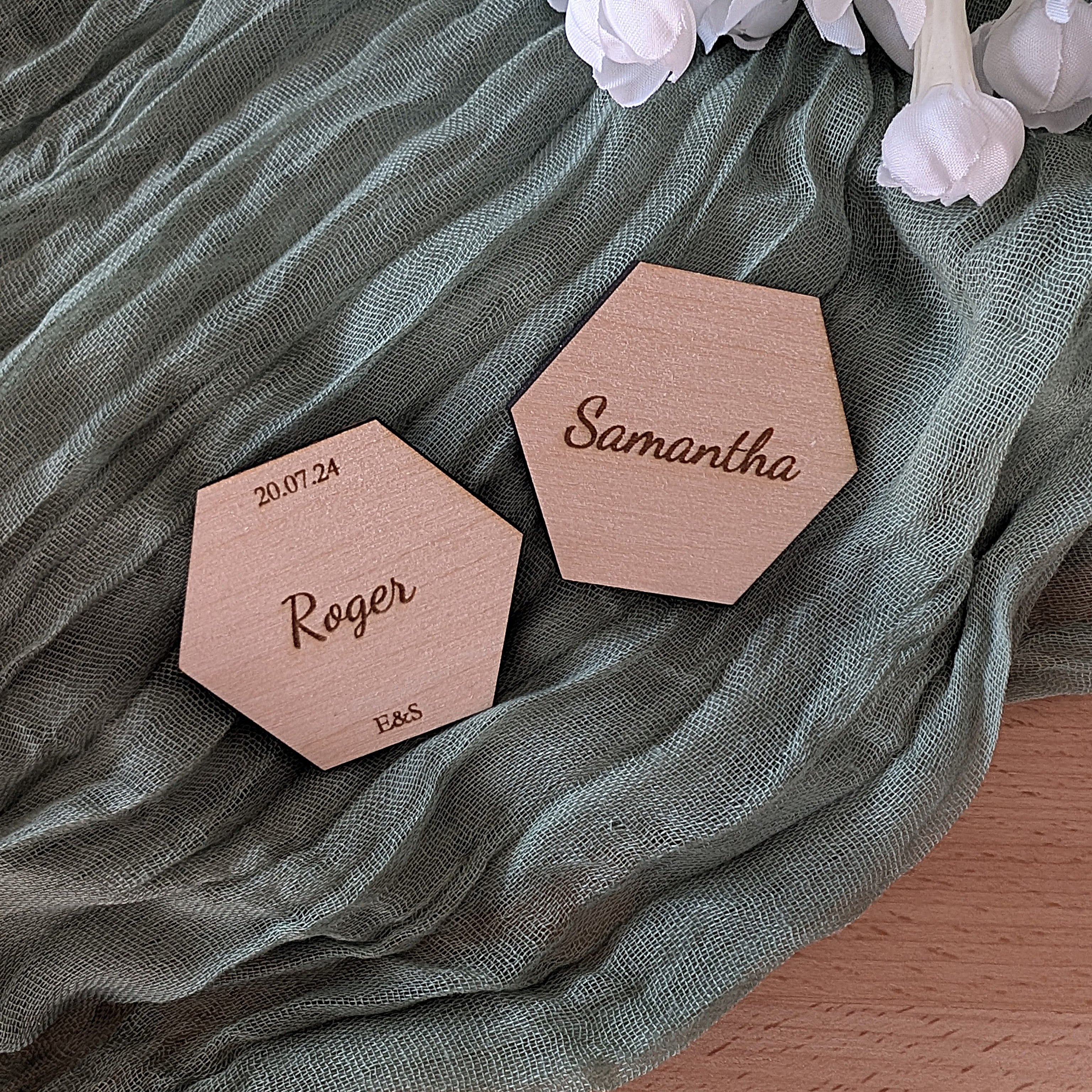 Two hexagonal wooden place names with engraved names on a green fabric background.
