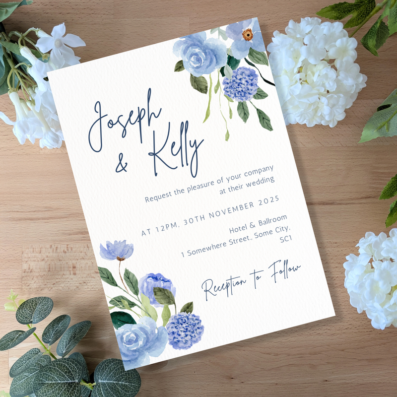 Wedding invitation card with floral design on a wooden surface with flowers around