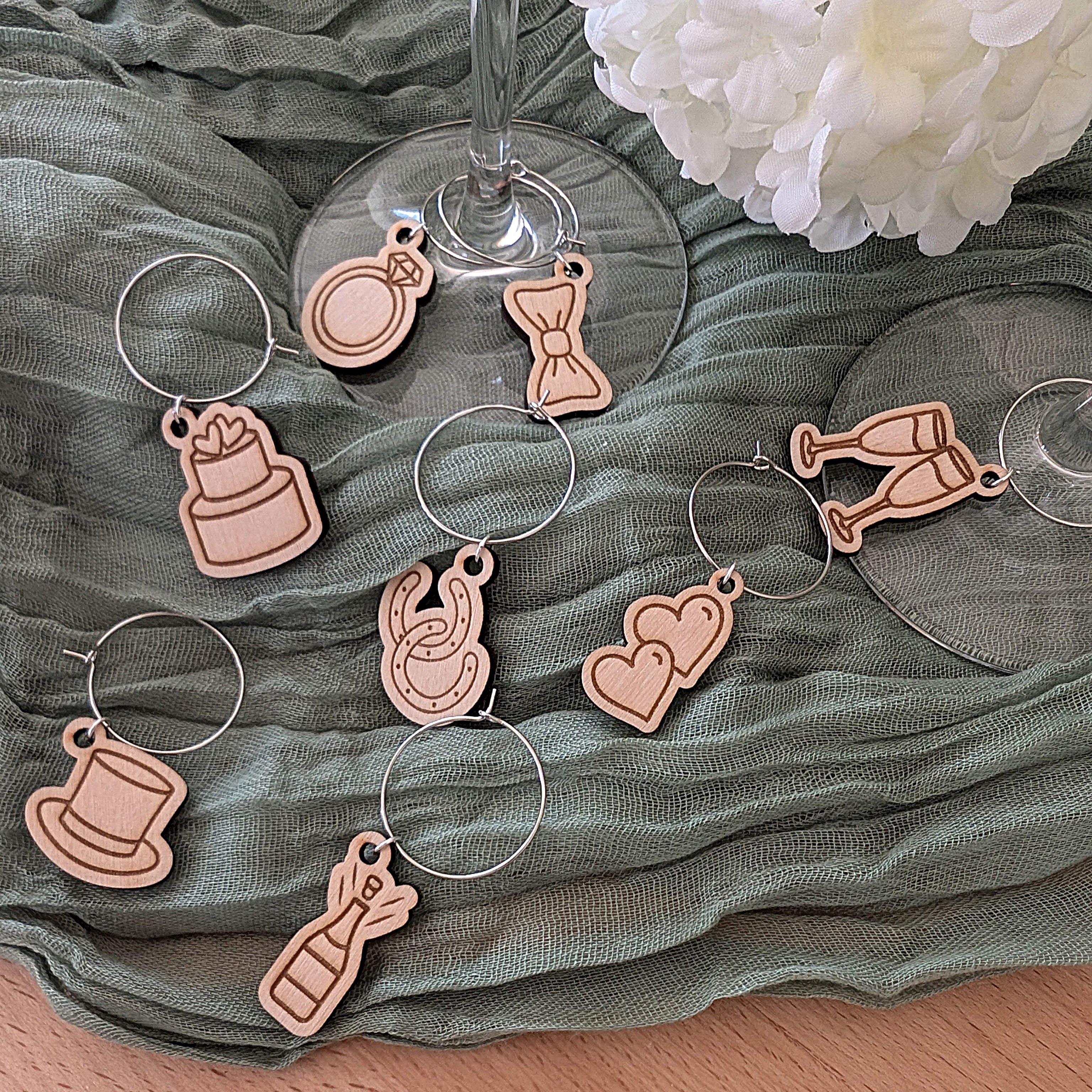 Set of decorative Christmas themed wine glass charms on a green fabric background with flowers.